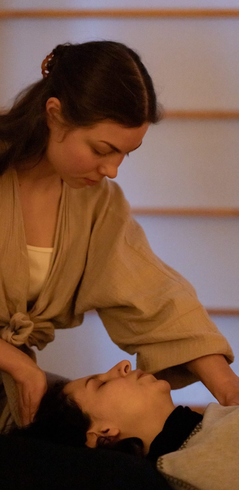 Breathwork Session in Leipzig Eine Frau führt eine entspannende Massage bei einer liegenden Person durch.